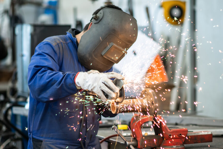 Operaio metalmeccanico che utilizza una saldatrice in officina, rappresentando il settore interessato dal rinnovo CCNL Area Meccanica 2024